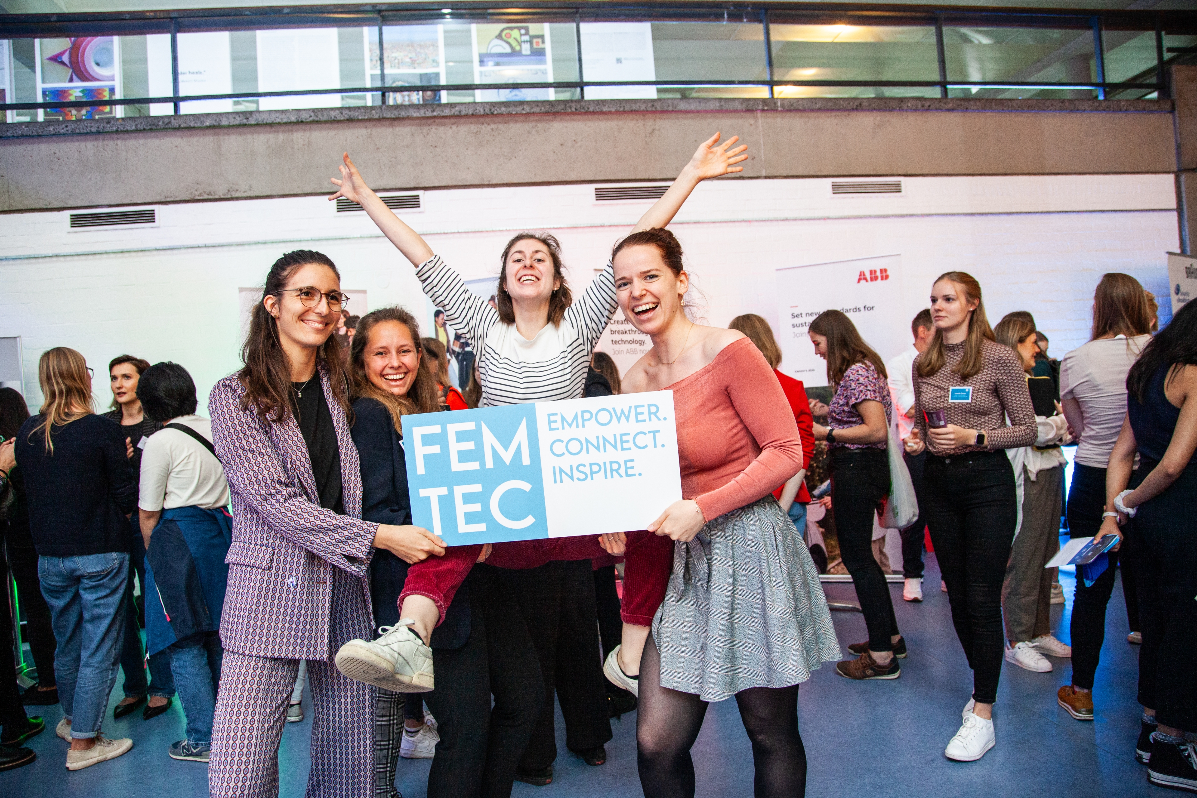Vier Studentinnen halten voller Freude und Enthusiasmus ein Schild mit dem Femtec-Logo.